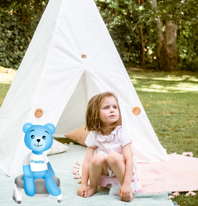 Młoda dziewczyna w jasnoróżowej sukience siedzi na kocu przed białym namiotem do zabawy w trawiastym, nasłonecznionym ogrodzie. Obok niej znajduje się niebieski miś z kreskówki z napisem Potette, siedzący na dziecięcym nocniku. Tło wypełniają drzewa i zieleń.